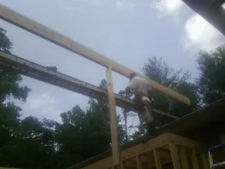 Carpenter setting a ridge beam over a new addition frame — Ice Dam Removal by Roofing Brothers in Prichard