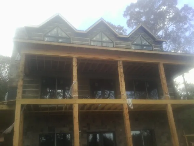 Dormers and porch framing on a large log home under construction — Roof Coating work by our crew in Prichard