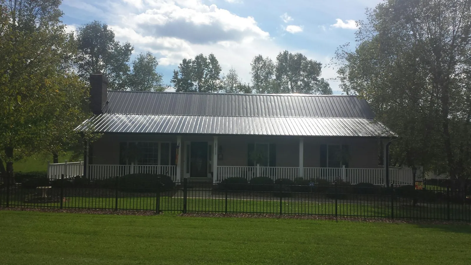Gray metal roof on a brick ranch with a full width front porch — Gutter Guard Installation work by our crew in Prichard