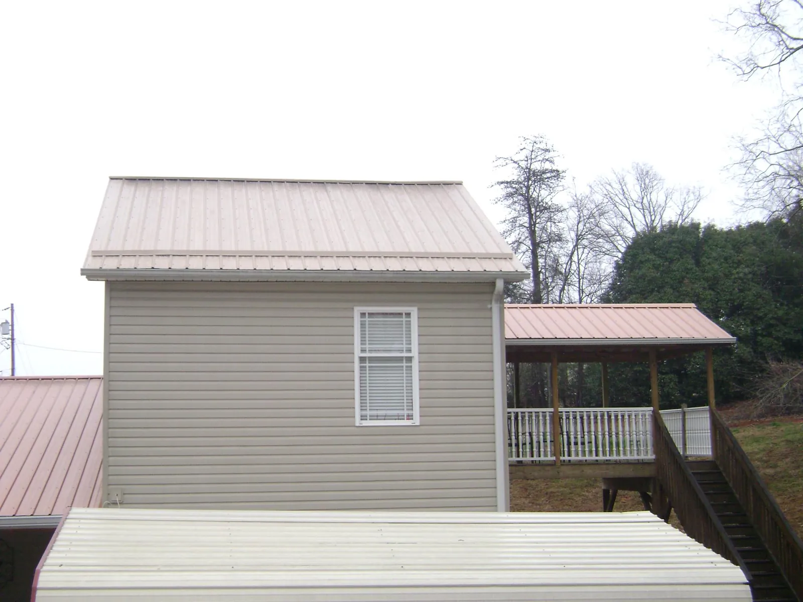 Tan metal roofs on a two story addition and attached porch, from a Roof Replacement job in Prichard