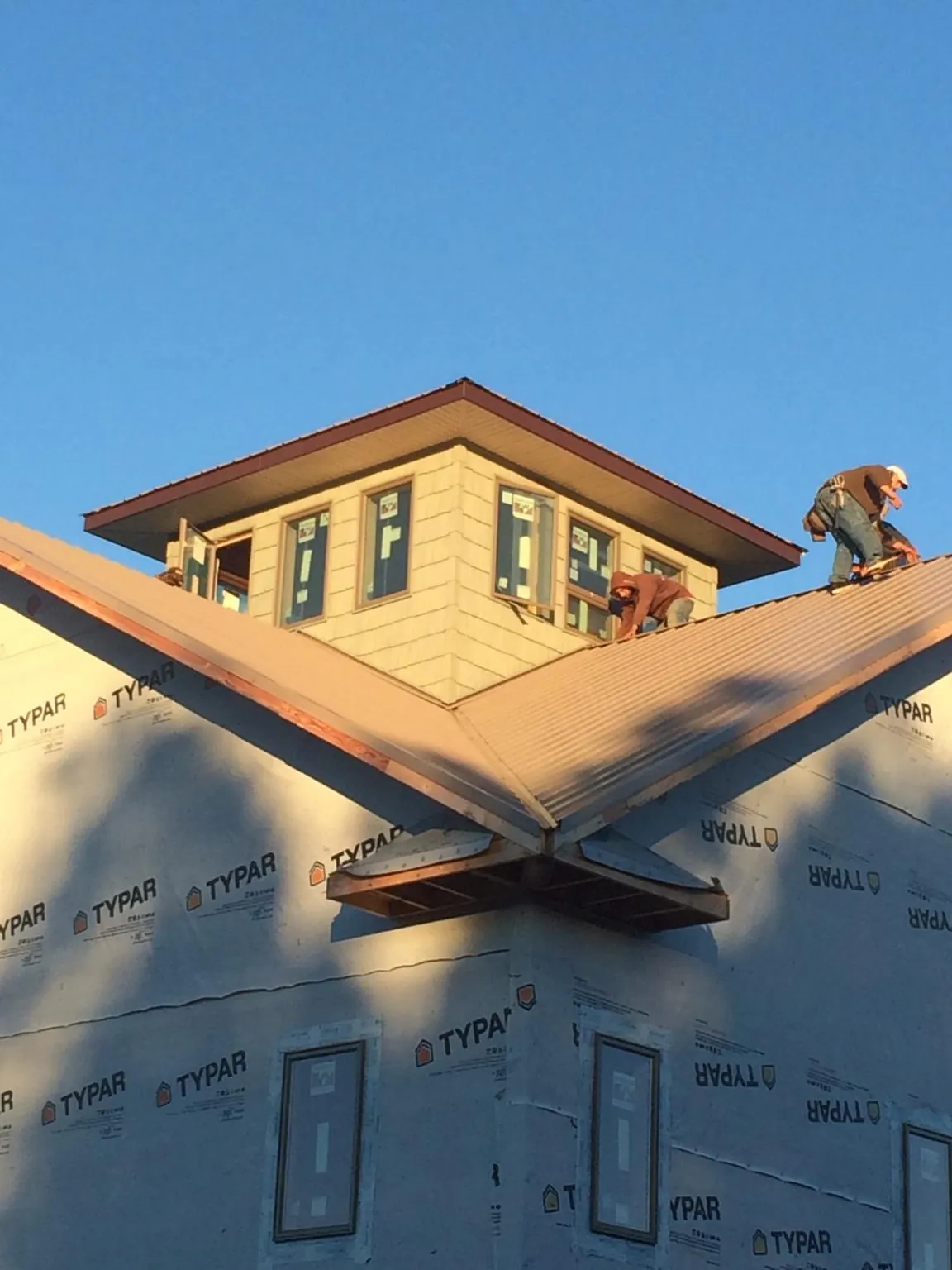 Roofers working around a rooftop cupola on a new metal roof at sunset — Roof Waterproofing in Prichard by Roofing Brothers